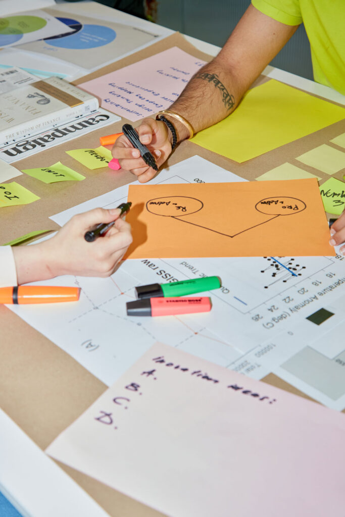 Two students discussing ideas during a hackathon, with their hands visible