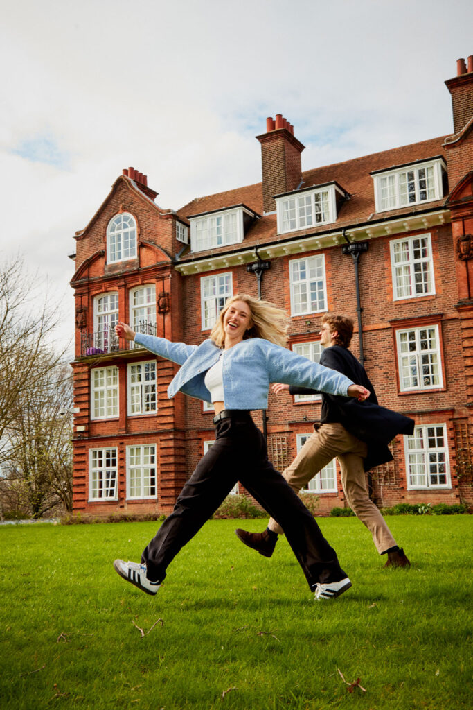 Regents University London students having fun jumping on the grass